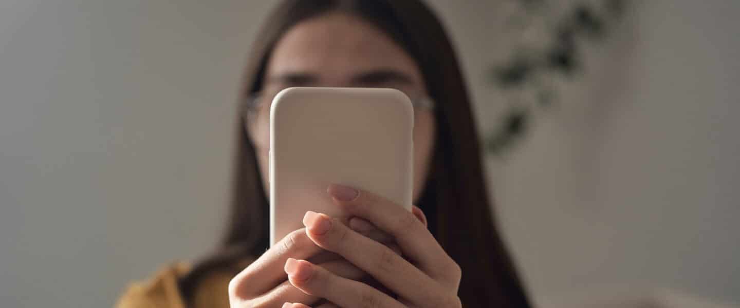 anonymous messaging on yik yak girl holding phone over face