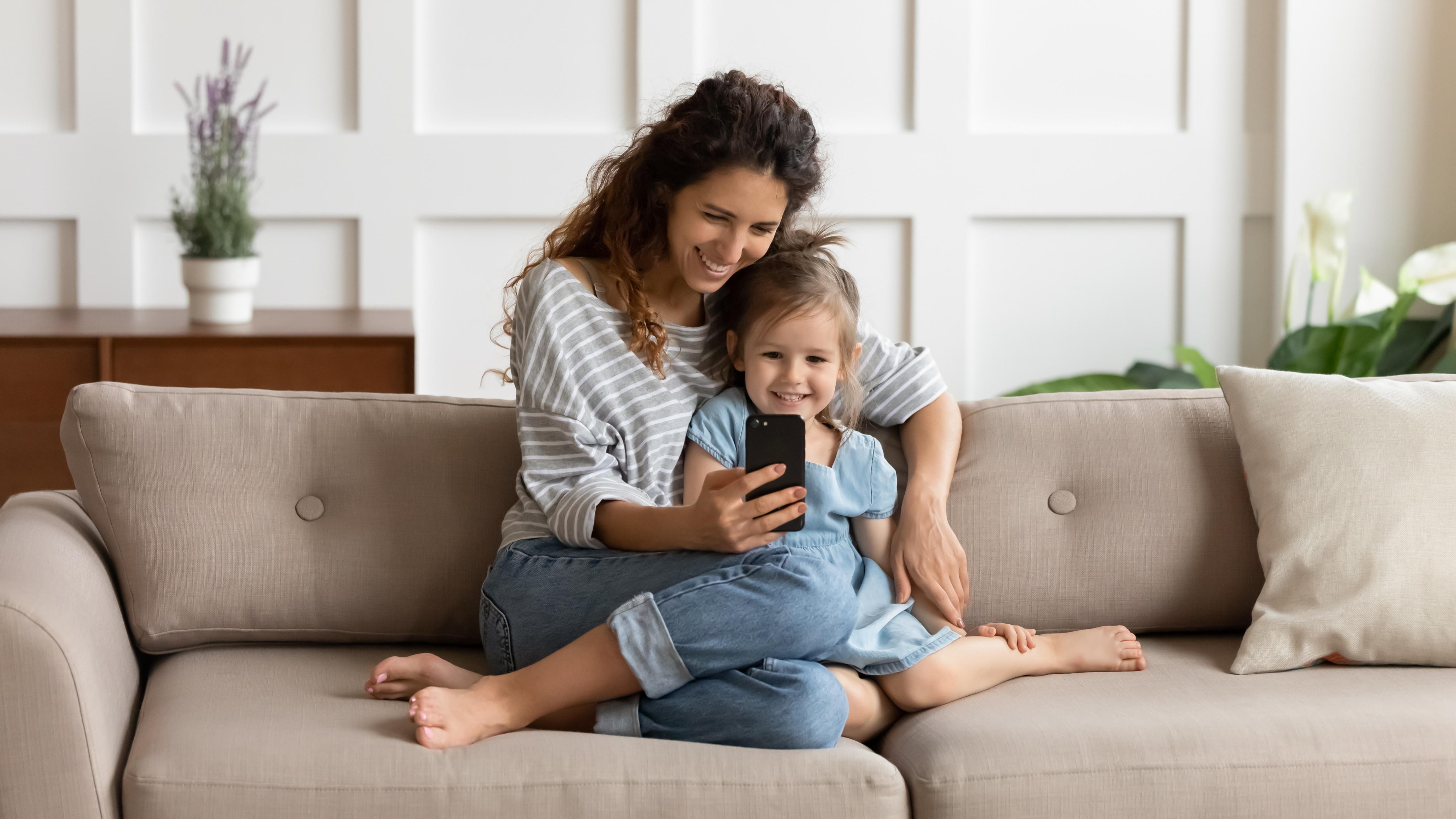 happy mom with her little girl looking at cell phone