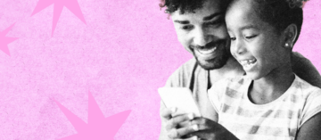 A dad and his daughter looking at a phone together and smiling