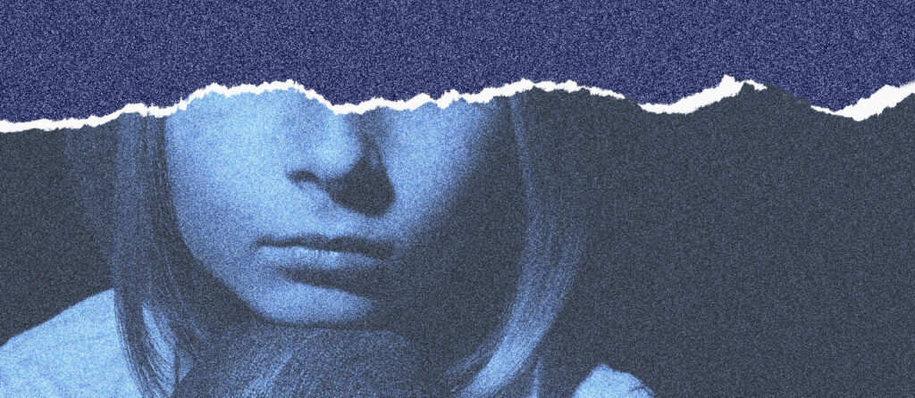 An image of a girl looking sad, resting her chin on her knee.