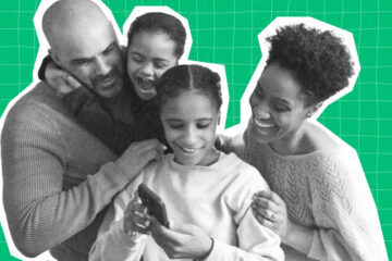 A family looks at a cell phone together, laughing.