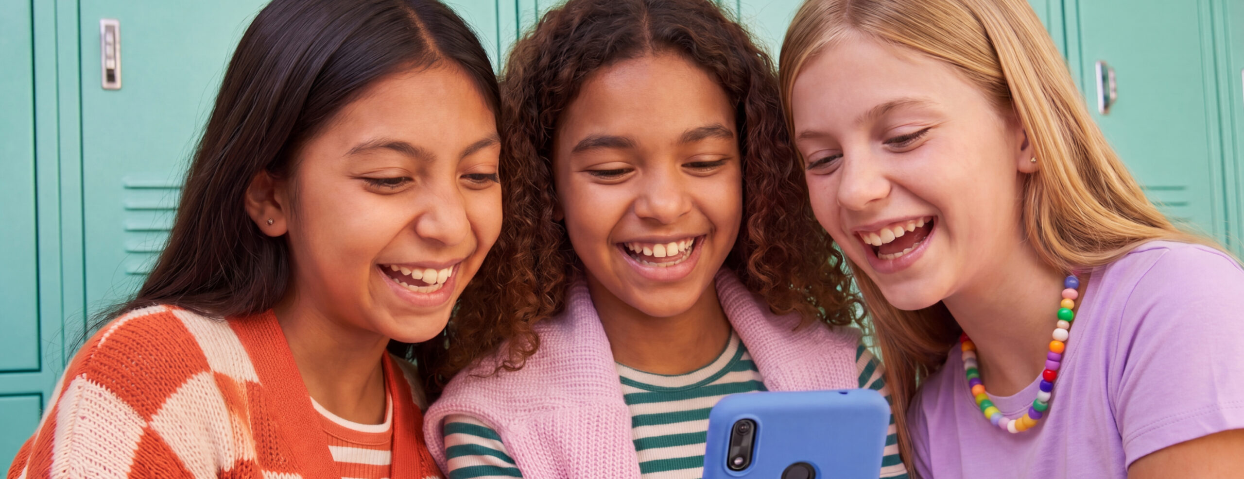 Three girls looking at a phone smiling