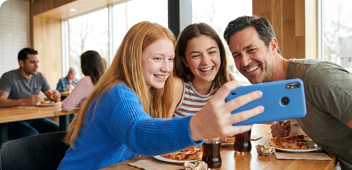 Father and two teen girls taking a selfie with a phone