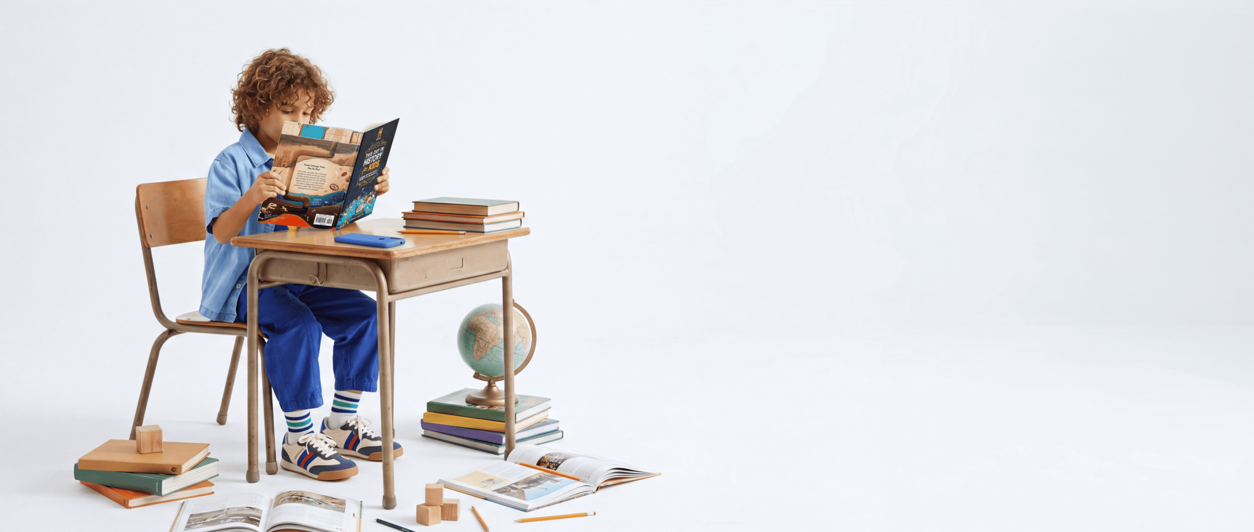 A kid reading at a school desk surrounded by books