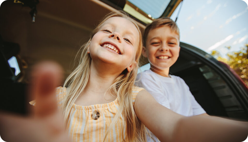 A young brother and sister getting out of a car