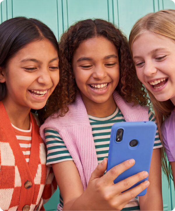 three friends laughing together at a Gabb Phone by their school lockers